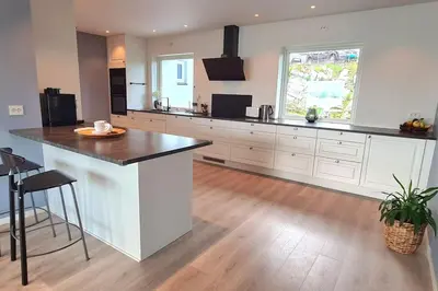 a kitchen with white cabinets and a black counter top at Villa with a view in Ålesund