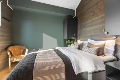 a bedroom with a large bed with a wooden wall at Riddertunets toppleilighet in Beitostøl