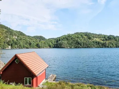 a red house on the shore of a lake at Holiday Home Askelund by Interhome in Uggdal