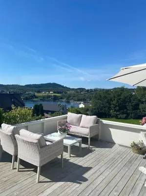 a patio with two chairs and a table and an umbrella at Drømmested for idylliske dager in Skjoldastraumen