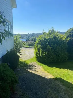 a house with some bushes next to a building at Drømmested for idylliske dager in Skjoldastraumen