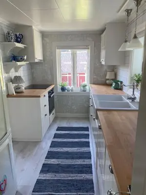 a kitchen with white cabinets and a blue rug at Drømmested for idylliske dager in Skjoldastraumen
