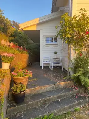 a house with a porch with a table and some flowers at Drømmested for idylliske dager in Skjoldastraumen
