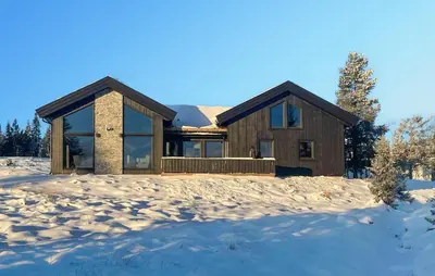 a log home in the snow with mountains in the background at 5 Bedroom Stunning Home In Løten in Løten
