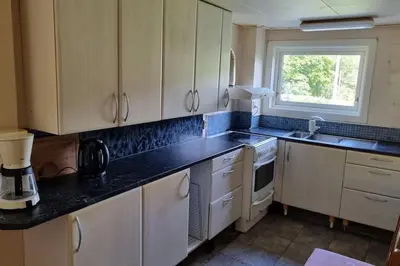 a kitchen with white cabinets and a black counter top at House in Austevoll in Austevoll