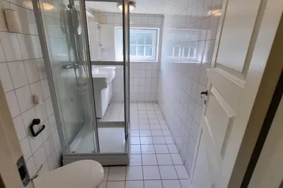a white bathroom with a shower and a toilet at House in Austevoll in Austevoll