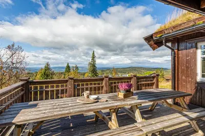 a wooden table on the deck of a cabin at HYTTEEVENTYR I VALDRES MED JACUZZI, 5 soverom, alpinbakke og skiløyper like ved! in Aurdal