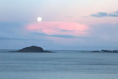 an island in the ocean with the moon in the sky at Private room in central homestay apartment with sea view in Ålesund