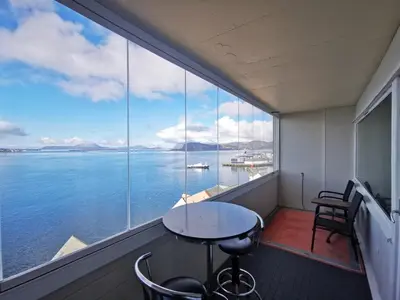 a balcony with a table and chairs and a view of the water at Private room in central homestay apartment with sea view in Ålesund