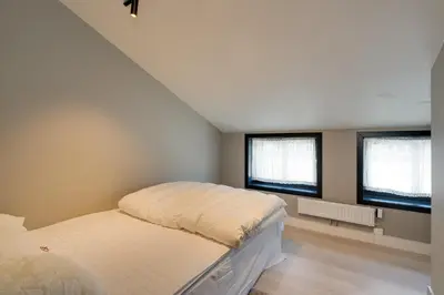 a bedroom with a bed and two windows at Stølstunets toppetasje in Beitostøl