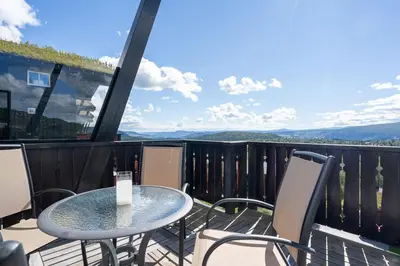 a table and chairs on a balcony with a view at Stølstunets toppetasje in Beitostøl