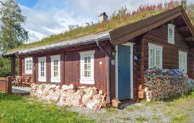 a log cabin with a grass roof and a pile of logs at 2 Bedroom Lovely Home In Oppdal in Oppdal