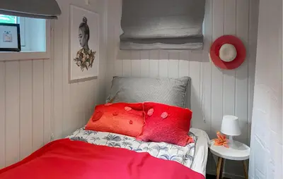 a bed with red pillows and a red blanket at Gorgeous Home In Sørbøvågen With Wifi in Saltbu