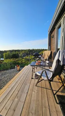 a wooden deck with a table and a chair on it at WayCamp Tustna in Leira