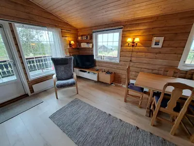 a living room with a table and a tv and windows at Trollbu by Norgesbooking - cabin at Golsfjellet in Sanderstølen