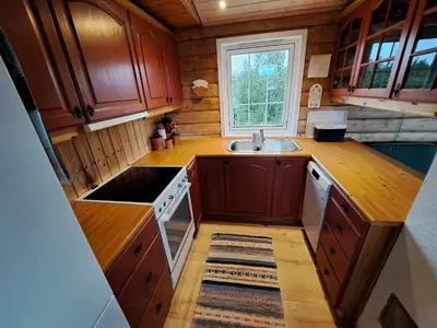 a kitchen with wooden cabinets and a sink and a window at Trollbu by Norgesbooking - cabin at Golsfjellet in Sanderstølen