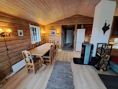a dining room with a table and wooden walls at Trollbu by Norgesbooking - cabin at Golsfjellet in Sanderstølen