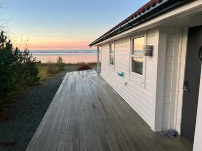 a house with a wooden walkway next to a building at Hytte i Lysøysund med 4 soverom, Ørland in Lysøysund