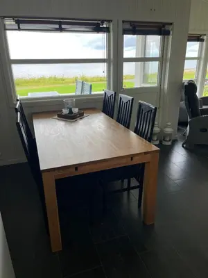 a wooden table and chairs in a room with windows at Hytte i Lysøysund med 4 soverom, Ørland in Lysøysund
