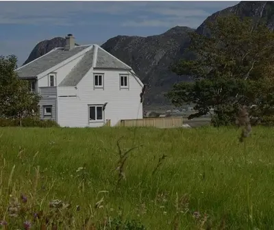 a white house in a field with mountains in the background at Haus Soltun-Was will man mehr! in Runde