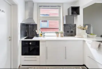 a white kitchen with white cabinets and a window at Koselig leilighet ved Solsiden in Trondheim