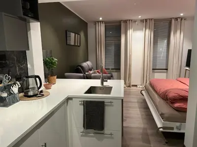 a kitchen with a sink and a bed in a room at Koselig leilighet ved Solsiden in Trondheim