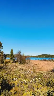 a field with a body of water in the background at Øyangen 3 in Rogne