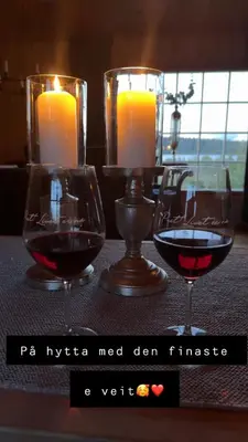 two glasses of wine sitting on a table with candles at Øyangen 3 in Rogne