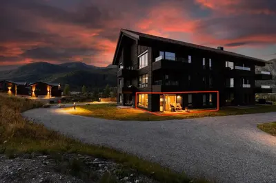 a large black building with a sunset in the background at Exclusive Ski In-Out apartment in Hemsedal next to Fyri Resort in Hemsedal