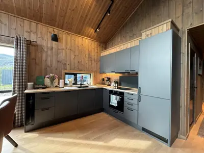 a kitchen with black and white appliances and wooden walls at Roaldsida Retreat in Stranda