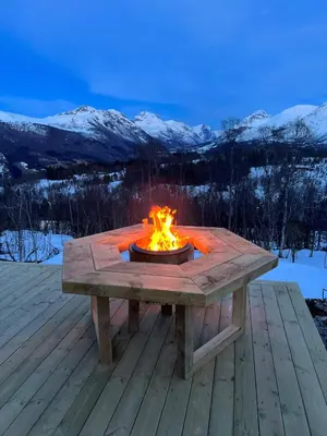 a fire pit on a deck with mountains in the background at Roaldsida Retreat in Stranda