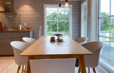 a wooden table in a kitchen with white chairs at 4 Bedroom Nice Home In Hildre in Hildre