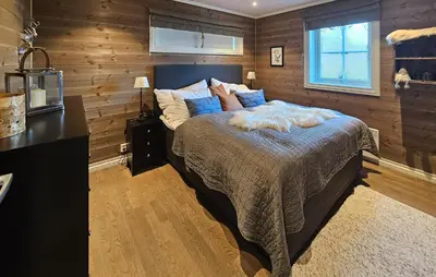 a bedroom with a large bed with wooden walls at 5 Bedroom Nice Home In Edland in Vågsli