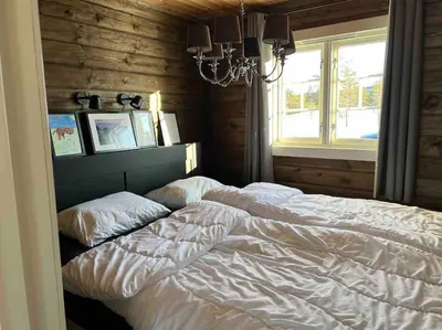 a bedroom with a white bed and a window at Delikat tømmerhytte på Blefjell in Flesberg