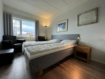 a bedroom with a bed and a chair and a window at Bitihorn hotellfølelse i sentrum in Beitostøl