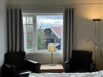 a bedroom with two chairs and a bed and a window at Bitihorn hotellfølelse i sentrum in Beitostøl