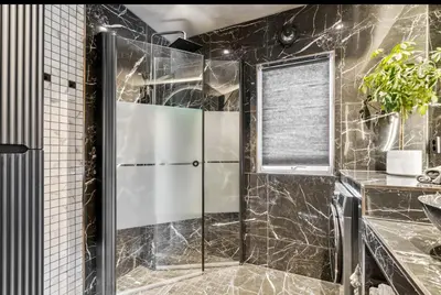 a bathroom with a shower with black tiles at Leilighet på to plan nyoppusset sentralt på Tyholt Trondheim in Trondheim