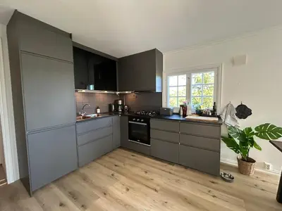a kitchen with gray cabinets and a wooden floor at Sjusjøstua by Norgesbooking - cabin close to cross country trails in Ringsaker