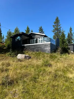a house sitting on top of a grassy hill at Sjusjøstua by Norgesbooking - cabin close to cross country trails in Ringsaker