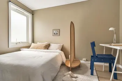 a bedroom with a bed and a surfboard next to a window at Sentral leilighet med parkering og peis in Bergen