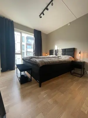 a bedroom with a bed and a large window at Splitter ny, romslig leilighet sentralt på Nyhavna leies ut in Trondheim