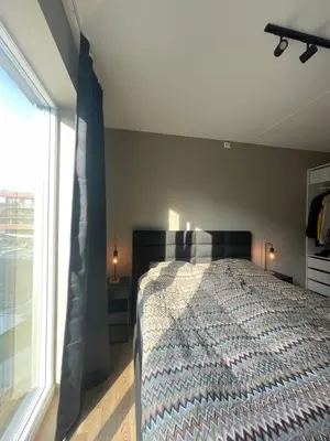 a bedroom with a bed and a large window at Splitter ny, romslig leilighet sentralt på Nyhavna leies ut in Trondheim