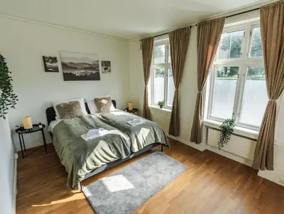 a bedroom with a bed and two windows at Stylish place in the heart of Bergen in Bergen