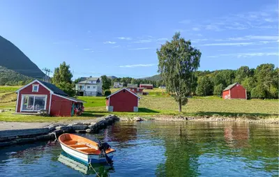a small boat sitting in the water next to houses at 3 Bedroom Stunning Home In Fiksdal in Fiksdal