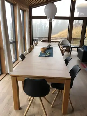 a large wooden table with chairs in a room with windows at Moderne hytte Sjusjøen in Sjusjøen