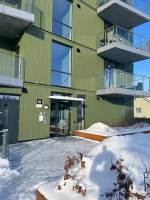a green building with snow in front of it at Heimdal Sentrum in Heimdal