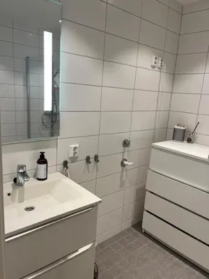 a white bathroom with a sink and a mirror at Heimdal Sentrum in Heimdal