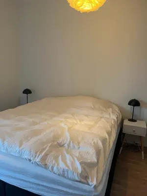a bedroom with a bed with white sheets on it at Heimdal Sentrum in Heimdal
