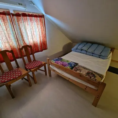 a small bedroom with a bed and two chairs at Captivating 6-Bed Cottage in Lismarka in Haugen