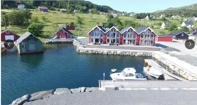 a boat is docked at a marina with houses at Måløy Fjordbuer moderne og luksuriøse med havutsikt in Måløy
